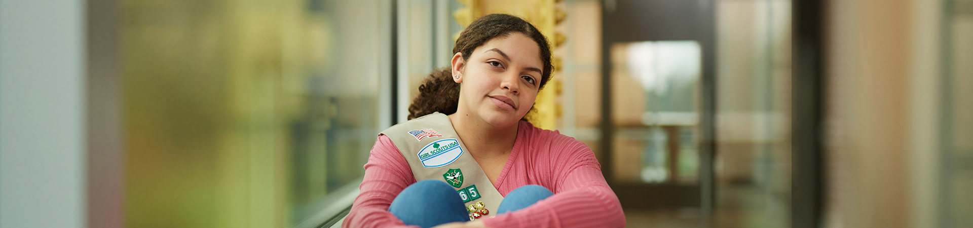  An Ambassador Girl Scout hugging her knees looking at the camera. 