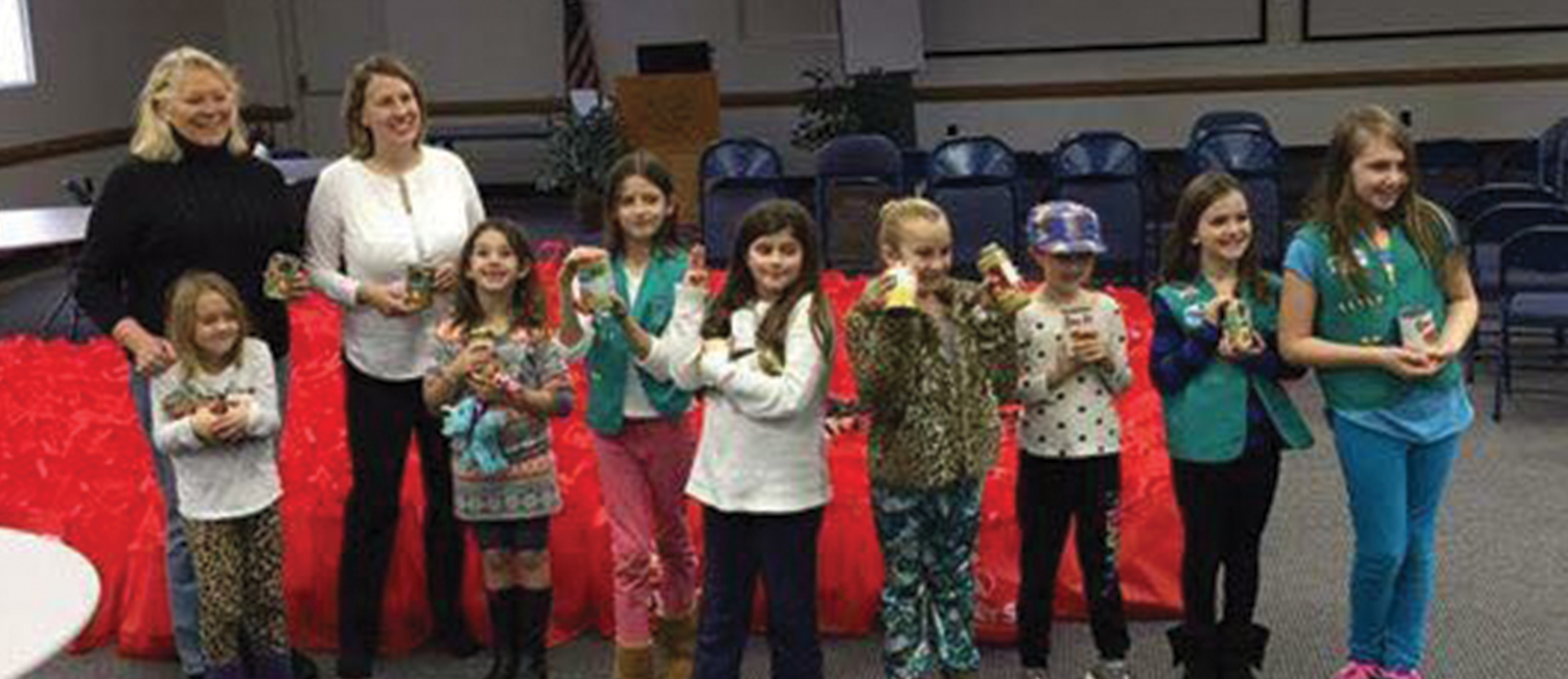  A troop of Girl Scouts posing with donated items 