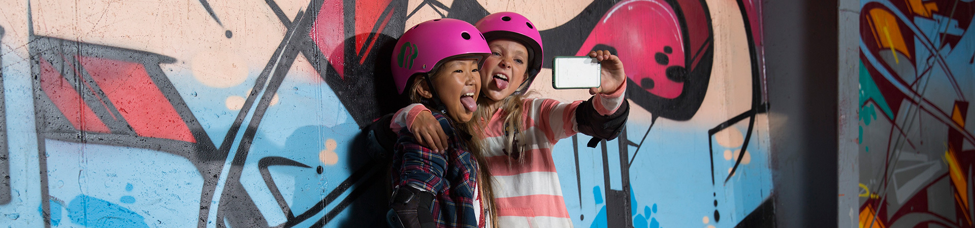  Two skater girls taking a selfie in front of a graffiti wall 