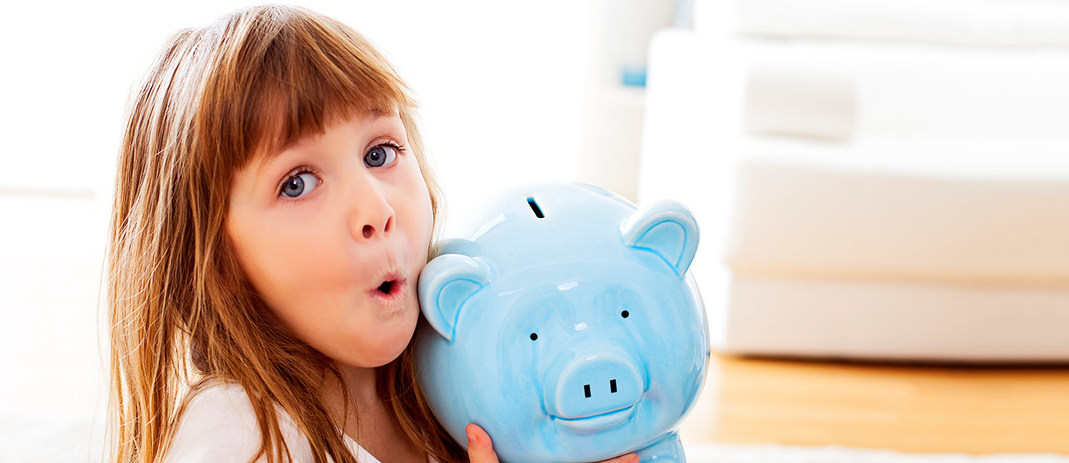  Little girl learning about money and proudly holding her blue piggy bank. 